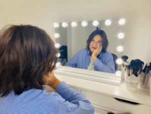 Femme transgenre devant miroir de maquilleuse